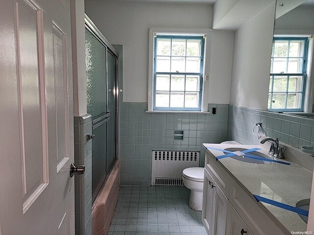 full bathroom with tile patterned floors, radiator, vanity, tile walls, and toilet