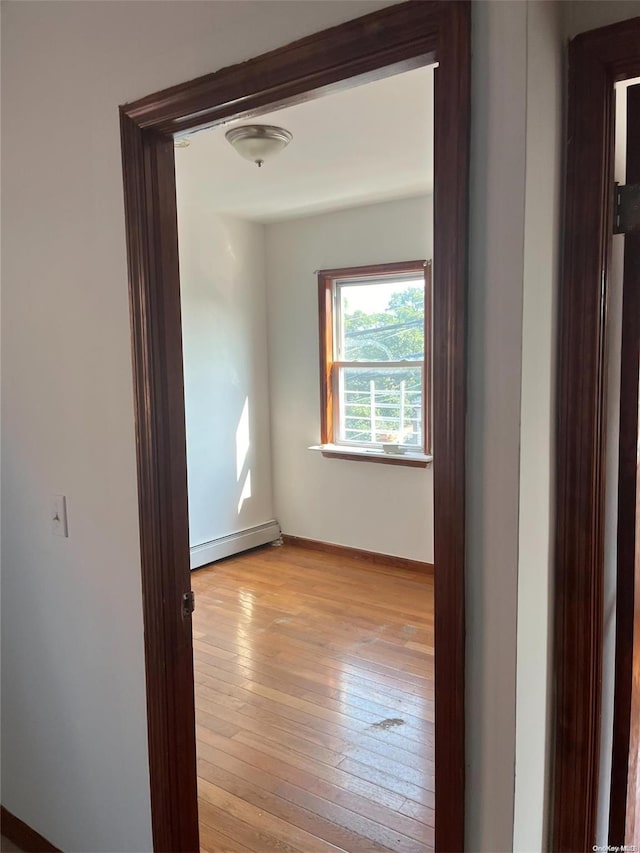 hall with baseboard heating and light hardwood / wood-style flooring