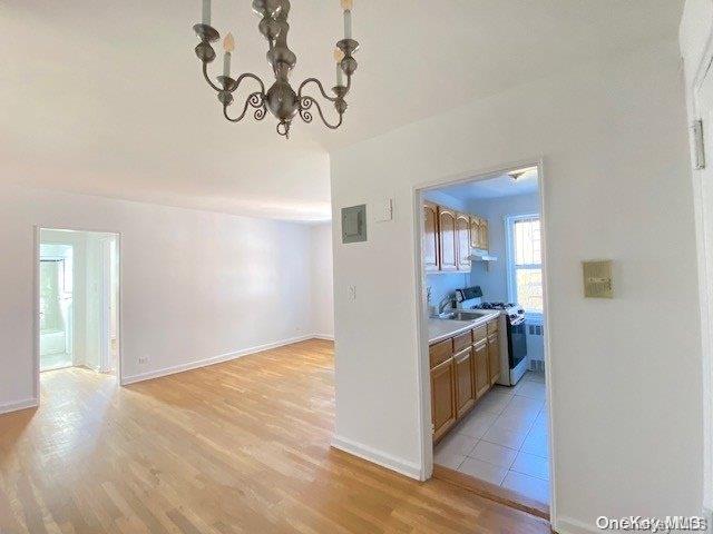 kitchen with sink, light hardwood / wood-style flooring, an inviting chandelier, and white range oven