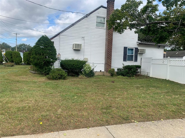 view of side of home with an AC wall unit and a yard