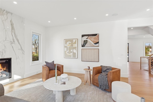 living area with a high end fireplace and light hardwood / wood-style floors