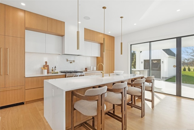 kitchen featuring plenty of natural light, white cabinets, an island with sink, and decorative light fixtures