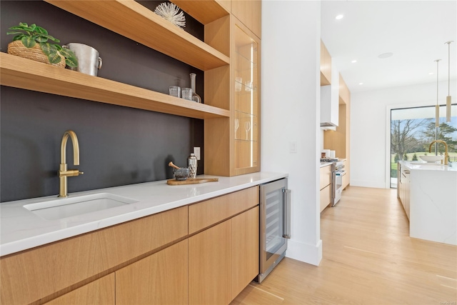 kitchen featuring light stone countertops, sink, hanging light fixtures, wine cooler, and high end range