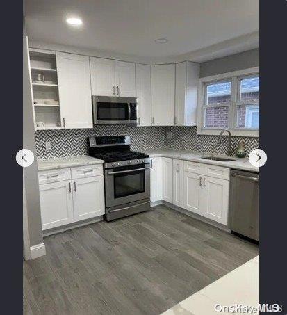 kitchen featuring decorative backsplash, appliances with stainless steel finishes, dark hardwood / wood-style flooring, sink, and white cabinetry