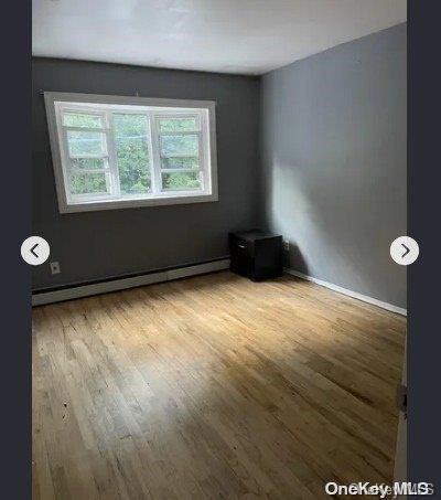 unfurnished room featuring a baseboard radiator and light hardwood / wood-style floors