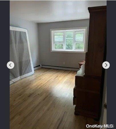 spare room featuring hardwood / wood-style flooring and a baseboard heating unit