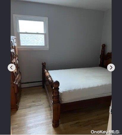 bedroom with light wood-type flooring and a baseboard radiator