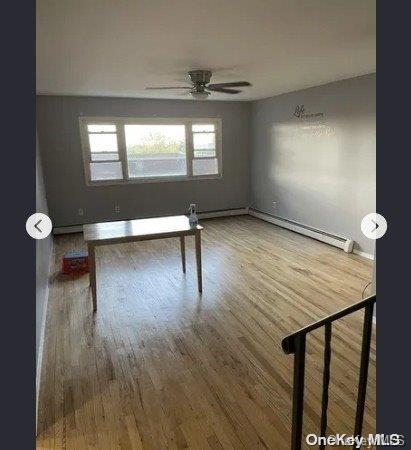 unfurnished room featuring ceiling fan, wood-type flooring, and baseboard heating