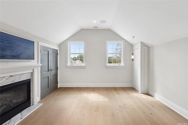 bonus room featuring a fireplace, light hardwood / wood-style floors, and vaulted ceiling