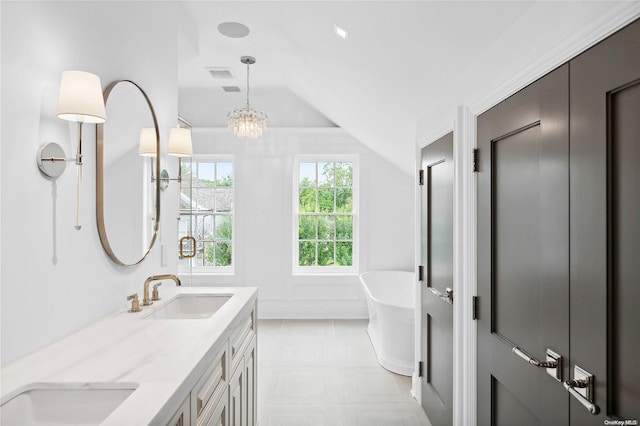 bathroom with vanity, lofted ceiling, a chandelier, and a bathing tub