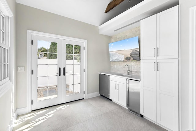 interior space with french doors, sink, appliances with stainless steel finishes, tasteful backsplash, and white cabinetry