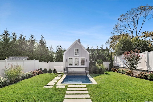 rear view of house with a lawn and a fenced in pool