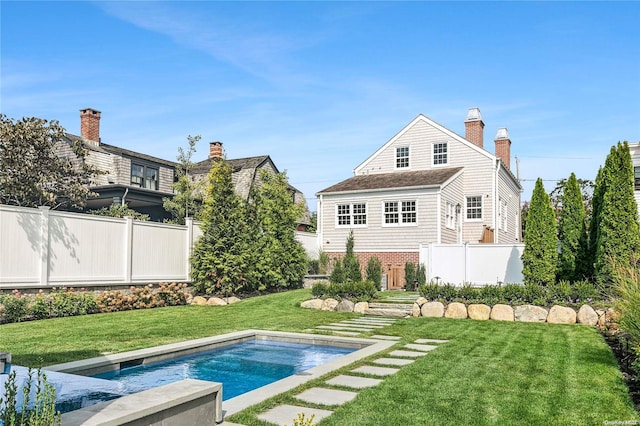 rear view of house with a fenced in pool and a yard