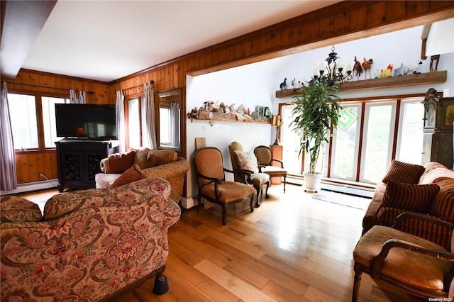 living room with a wealth of natural light, crown molding, light hardwood / wood-style floors, and wood walls