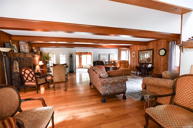 living room with wood walls, beamed ceiling, and light hardwood / wood-style floors