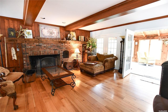 living room featuring wooden walls, crown molding, beamed ceiling, and light hardwood / wood-style floors