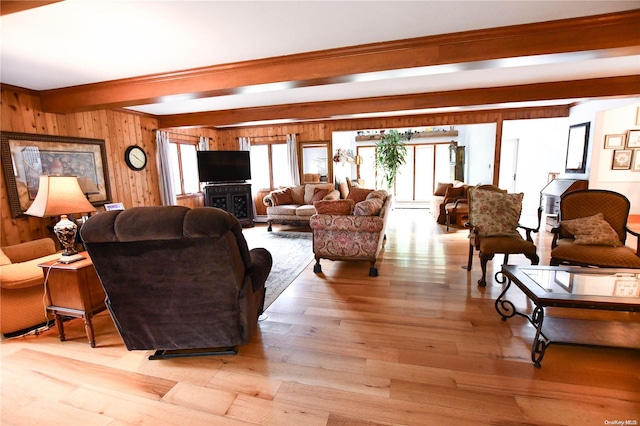 living room featuring beamed ceiling, light hardwood / wood-style floors, and wooden walls