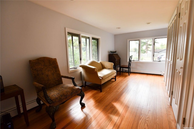 sitting room with a baseboard heating unit, a wealth of natural light, and light hardwood / wood-style flooring