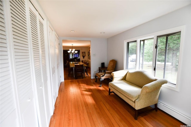 sitting room with hardwood / wood-style flooring, an inviting chandelier, and a baseboard heating unit