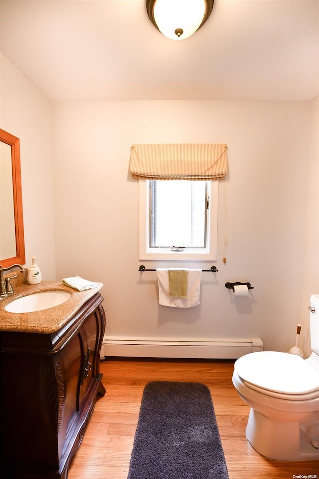 bathroom with hardwood / wood-style flooring, vanity, toilet, and a baseboard radiator