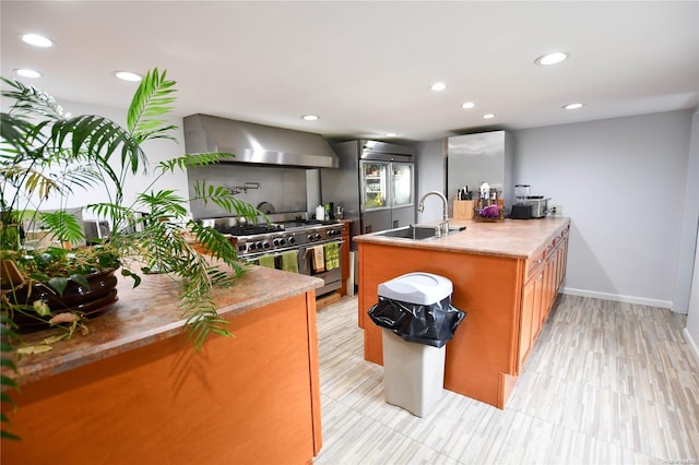 kitchen featuring sink, range with two ovens, and wall chimney range hood