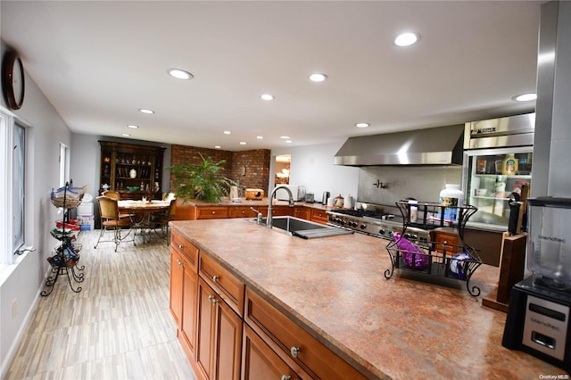 kitchen featuring sink and wall chimney range hood