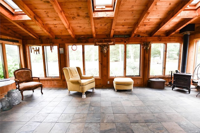 sunroom / solarium featuring a wood stove, vaulted ceiling with skylight, and wood ceiling