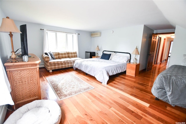 bedroom featuring a wall mounted AC and wood-type flooring