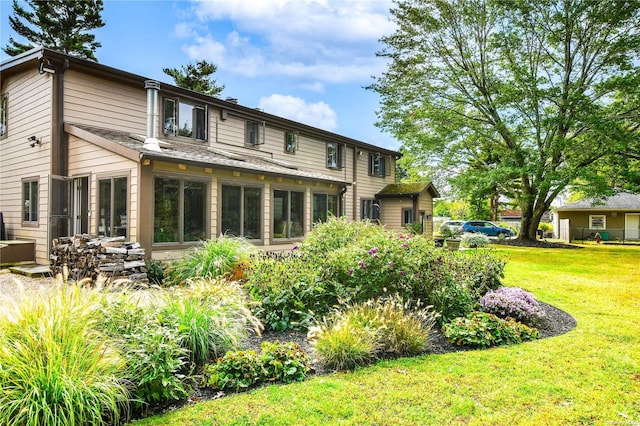 rear view of property featuring a yard and a sunroom