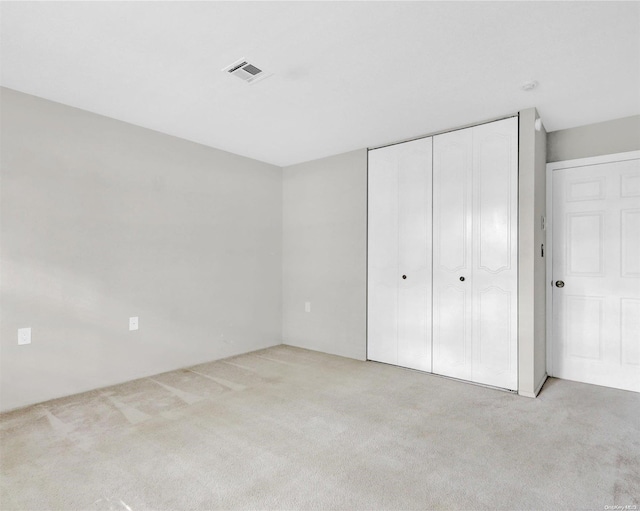 unfurnished bedroom with light carpet and a closet