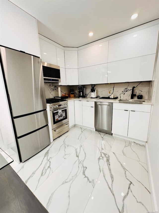 kitchen featuring white cabinetry, sink, light stone counters, decorative backsplash, and appliances with stainless steel finishes