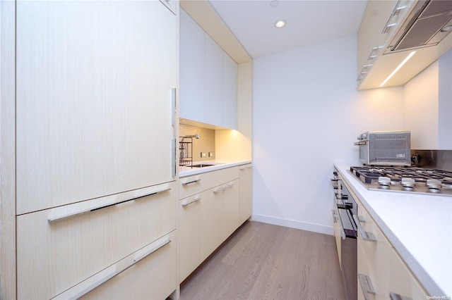 kitchen featuring sink, decorative backsplash, light wood-type flooring, white cabinetry, and stainless steel gas cooktop