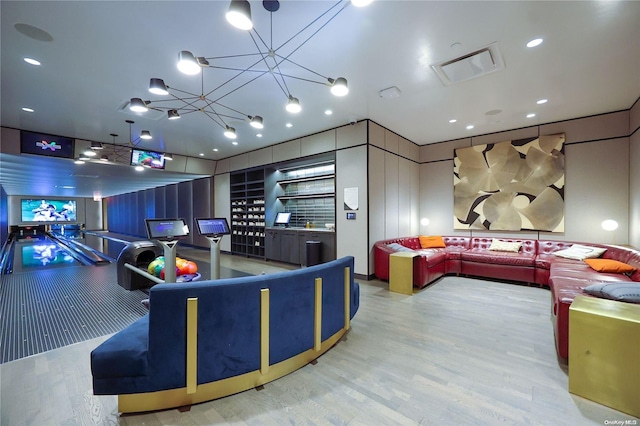 game room with hardwood / wood-style flooring, a bowling alley, and an inviting chandelier