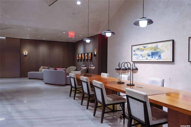 dining space featuring a towering ceiling and wooden walls