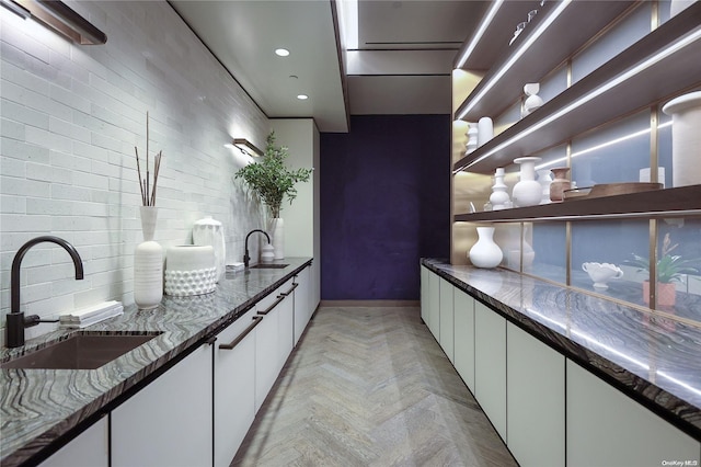 kitchen with white cabinets, sink, and light parquet floors