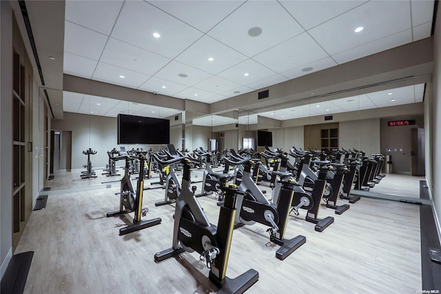 exercise room with light hardwood / wood-style floors and a drop ceiling