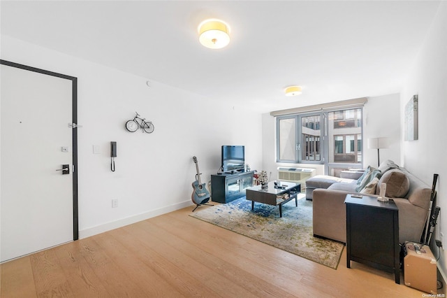 living room featuring an AC wall unit and light hardwood / wood-style flooring