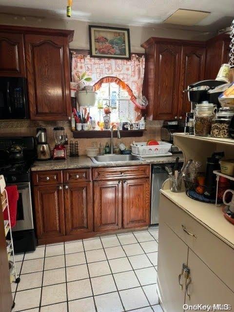 kitchen with tasteful backsplash, sink, light tile patterned flooring, and black appliances