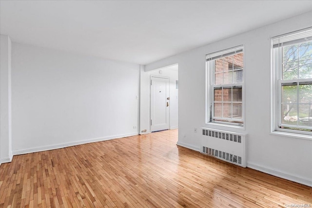 spare room with radiator heating unit and light hardwood / wood-style floors