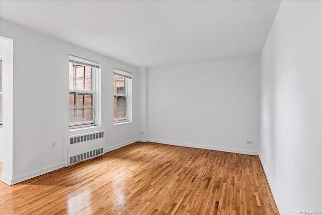 empty room featuring radiator and light hardwood / wood-style flooring