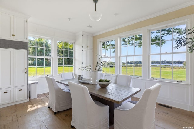 dining area with crown molding, plenty of natural light, and light wood-type flooring