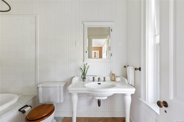 bathroom with a washtub, hardwood / wood-style flooring, and toilet