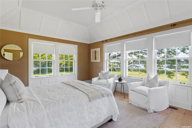 bedroom with ceiling fan, light hardwood / wood-style floors, and vaulted ceiling