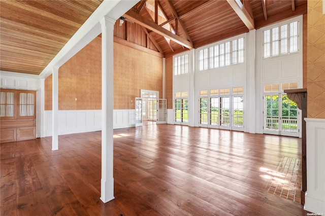 unfurnished living room with beamed ceiling, hardwood / wood-style floors, high vaulted ceiling, and wood ceiling