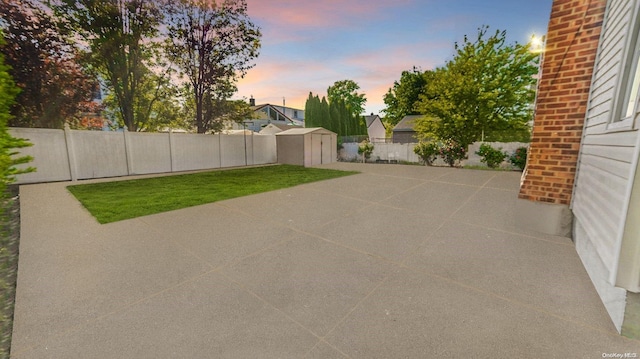 patio terrace at dusk with a storage unit and a yard