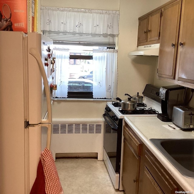 kitchen with sink, white appliances, and radiator heating unit