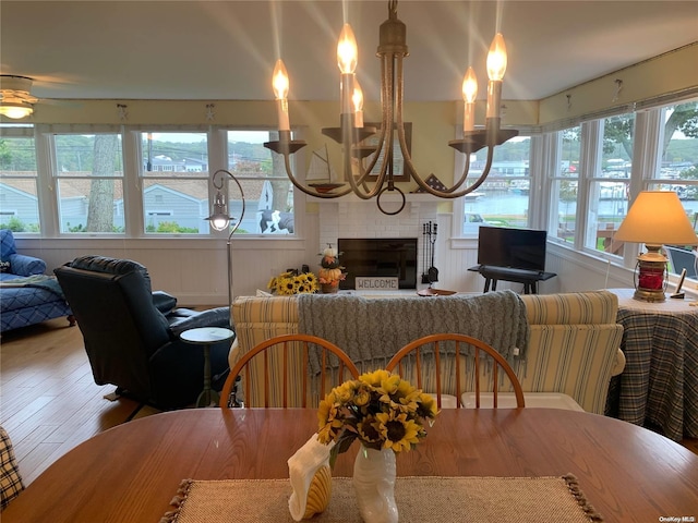 dining space featuring a healthy amount of sunlight, wood-type flooring, and a brick fireplace