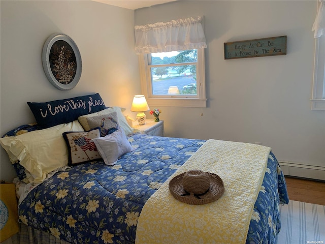 bedroom featuring wood-type flooring and a baseboard heating unit