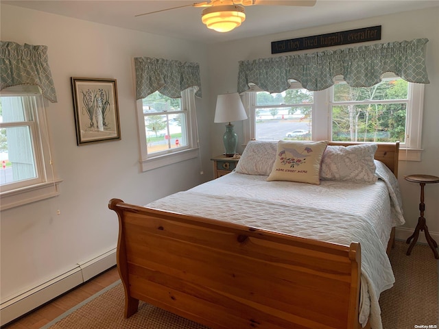 bedroom with hardwood / wood-style floors, a baseboard radiator, and ceiling fan