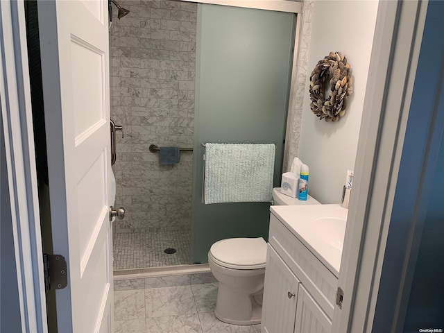 bathroom with tiled shower, vanity, and toilet